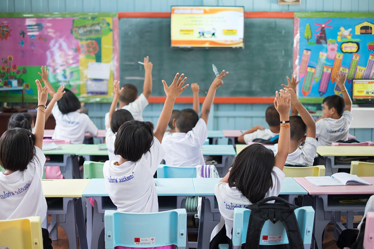 Student hands up asking a question in class at the elementary school. Education concept.