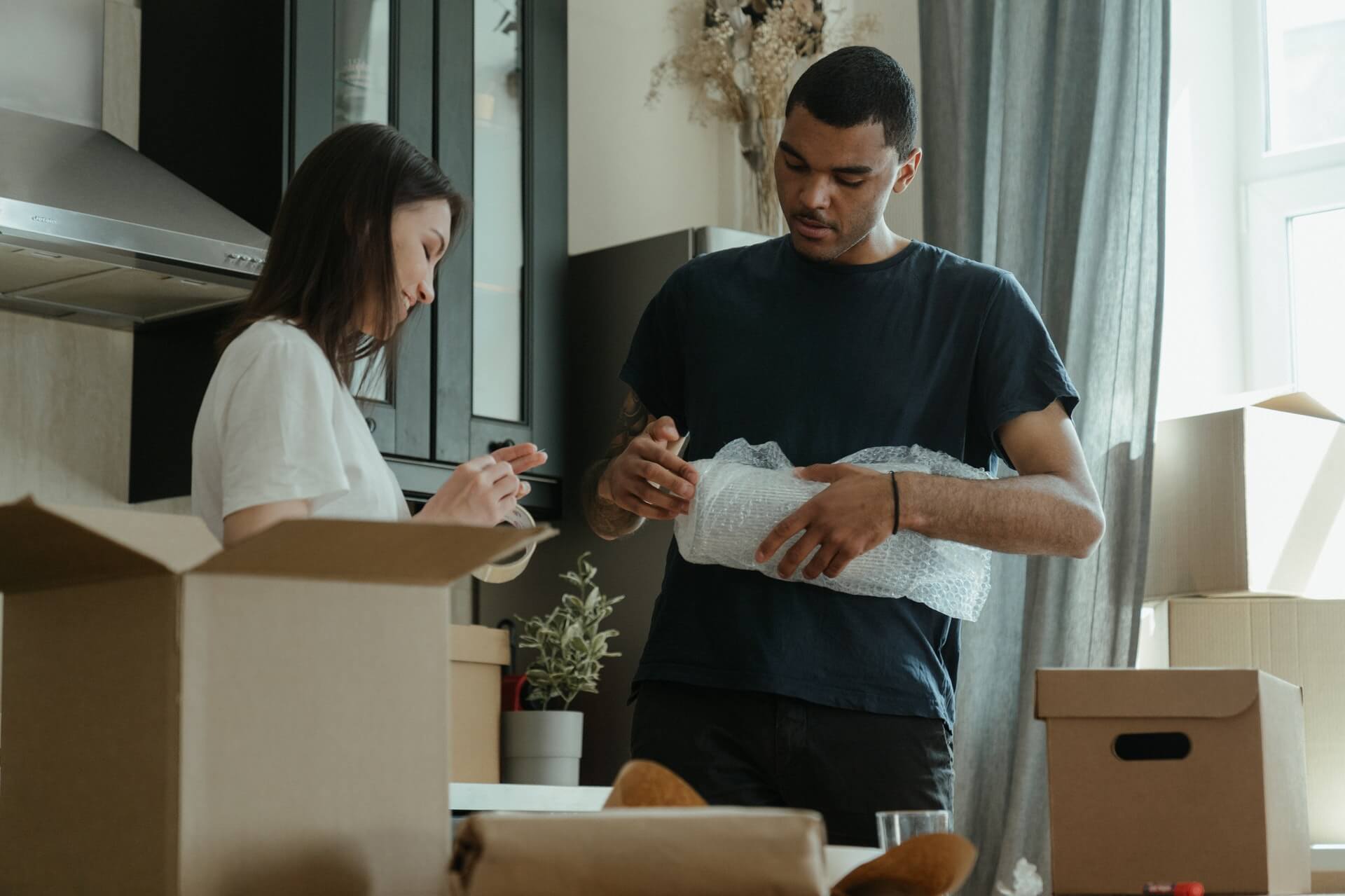 A young couple packaging their stuff into bubble wrap and boxes