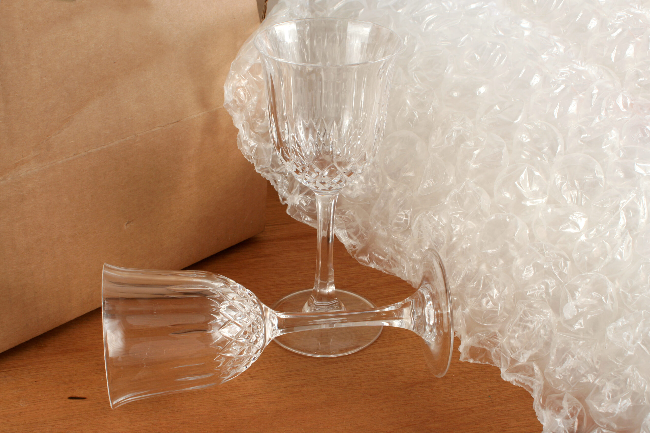 Two crystal glasses next to some bubble wrap and boxes