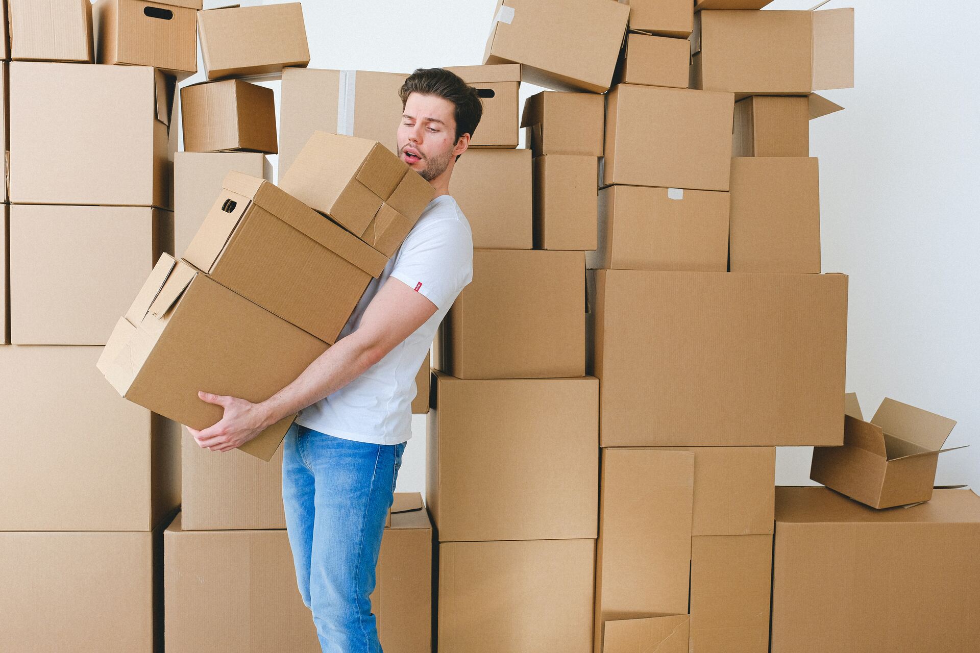 Man struggling to carry too many cardboard boxes