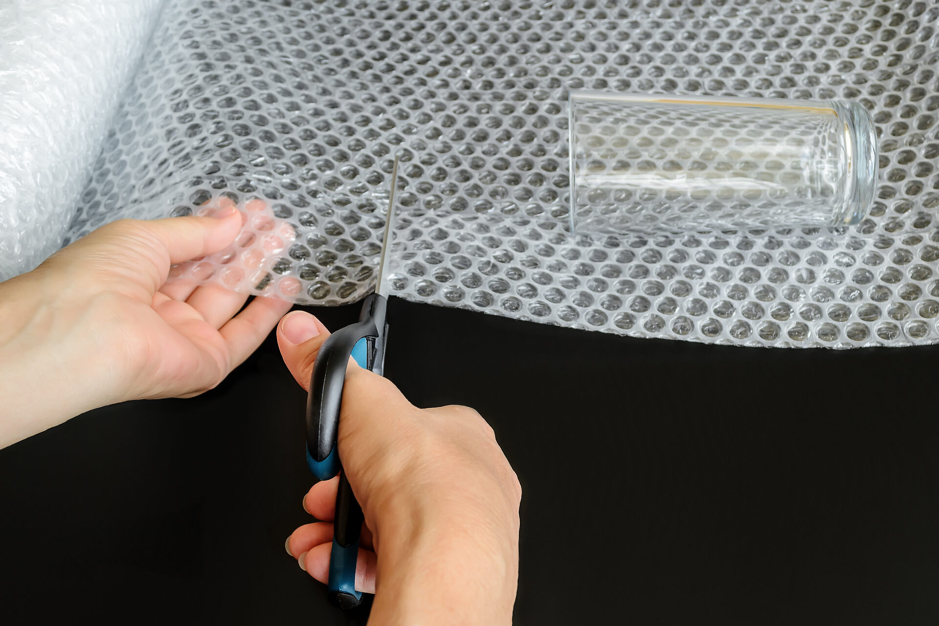 Person cutting bubble wrap around the glass