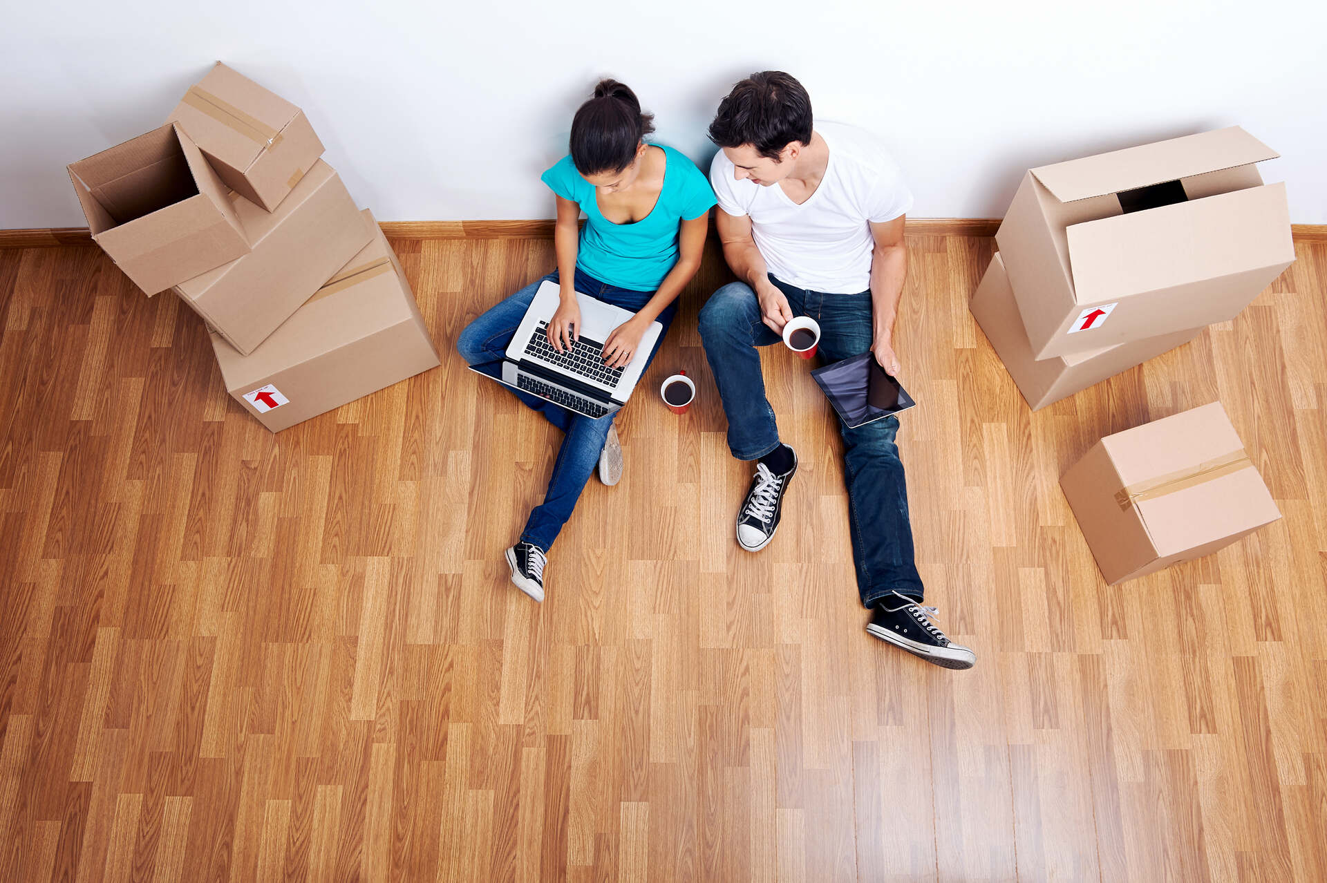 A young couple sitting on the floor, making a relocation plan