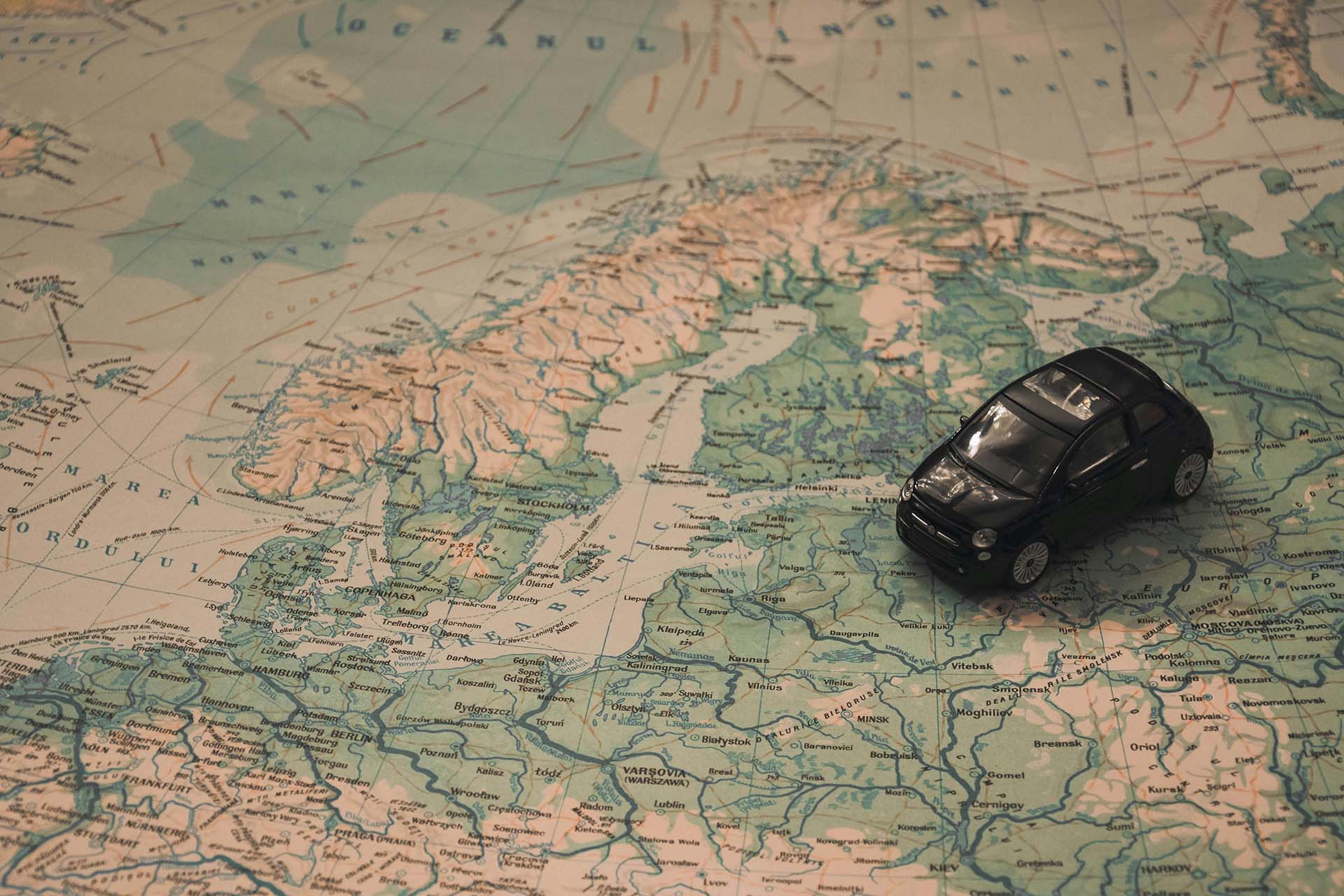A black toy car sitting on a map of Scandinavia