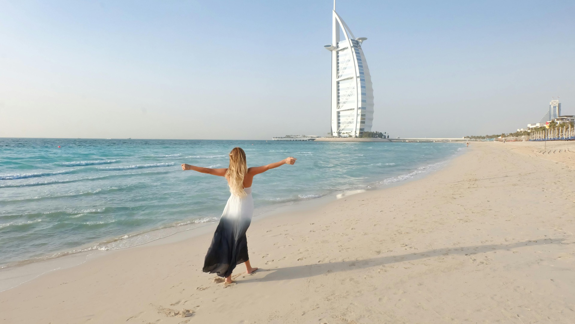 Woman in a dress walking on a sunny beach in Dubai