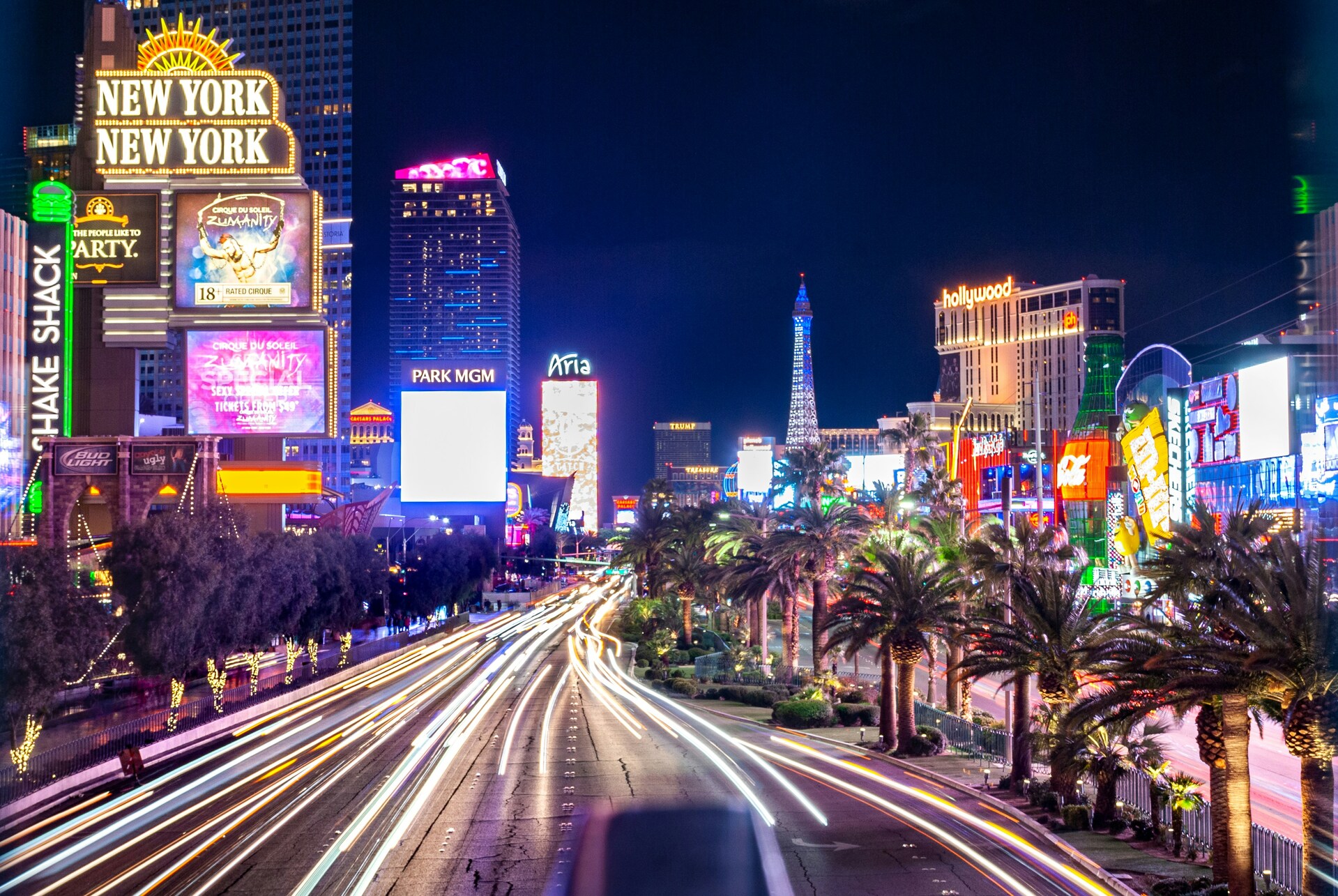 Long exposure night photography of Las Vegas Strip with neon lights and city traffic motion trails.