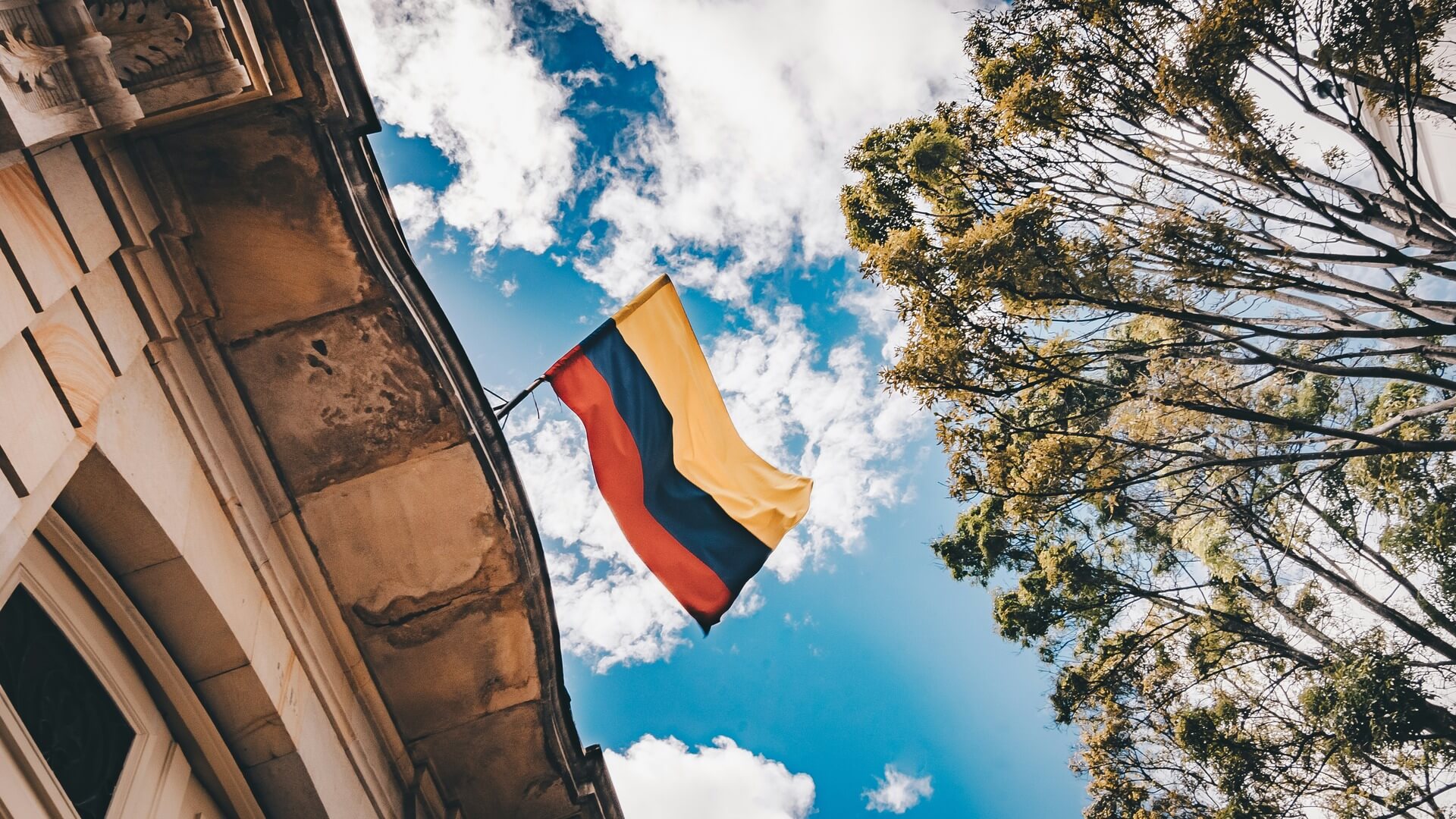 Yellow, blue, and red national flag fluttering against a clear open sky.